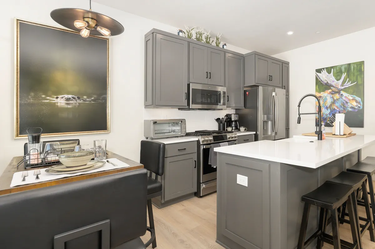 A contemporary kitchen and dining area with a central island, stylish dining table setup, and eye-catching wall art. The space is filled with warm natural light, creating an inviting atmosphere for cooking, sharing meals, and entertaining.