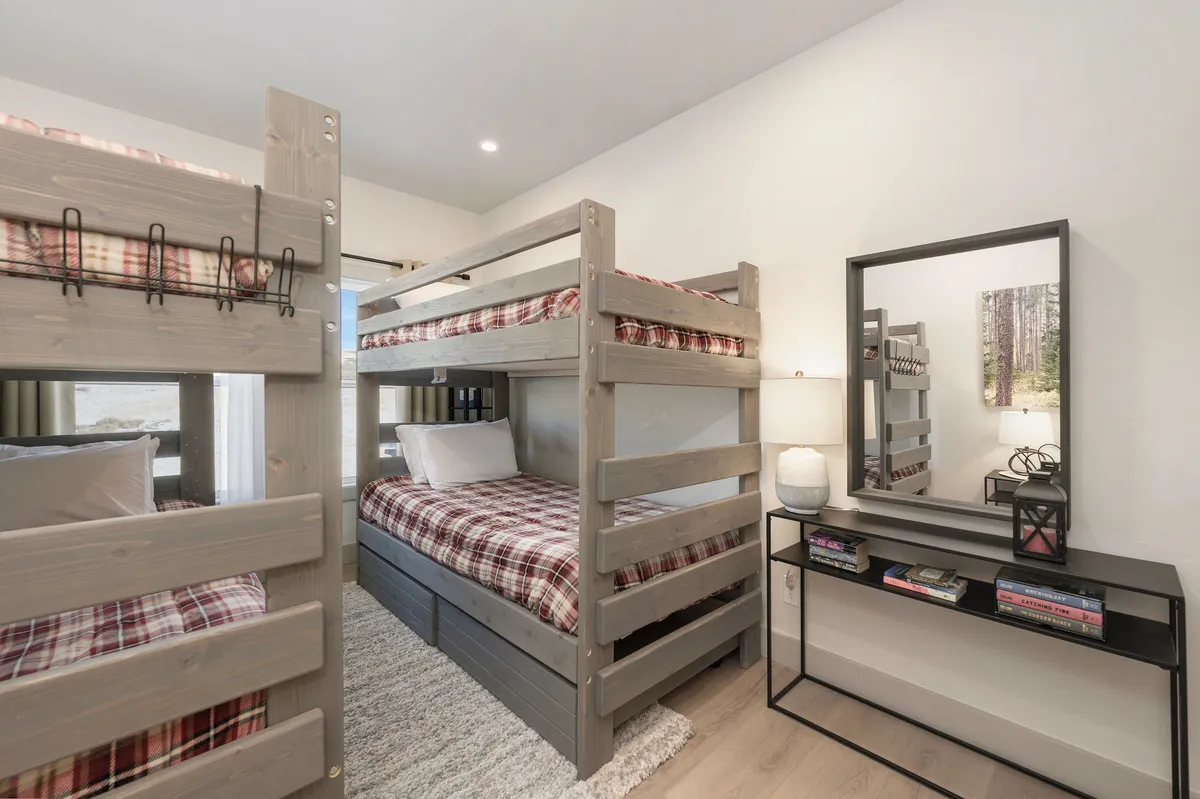 A welcoming, family-friendly bunk room featuring sturdy bunk beds, a soft rug, and gentle lighting. The space feels safe and playful, offering a cozy sleepover spot designed with children in mind.