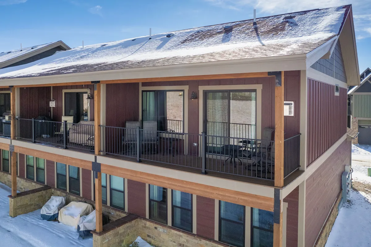 The exterior of a modern townhouse with a prominent balcony, large windows, and a welcoming roofline. The balcony hints at a comfortable, scenic spot for guests to relax and enjoy the outdoors, blending architecture with the surrounding landscape.