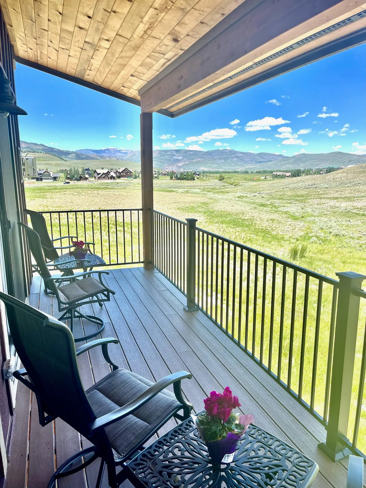 An outdoor seating area with comfortable chairs and a decorative table is set against a vast, open landscape. The scene invites relaxation, conversation, and appreciation of the surrounding nature, with a flower pot adding a homely touch.